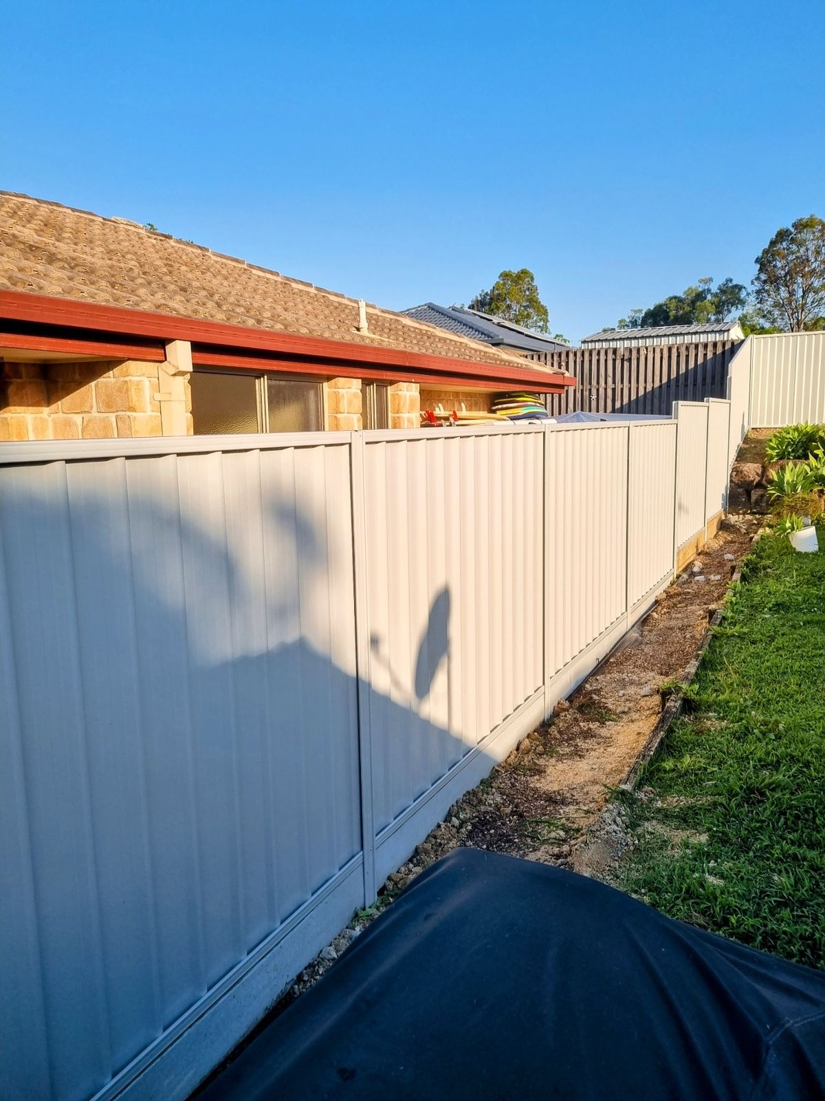 Cream Colorbond boundary fence with a level base