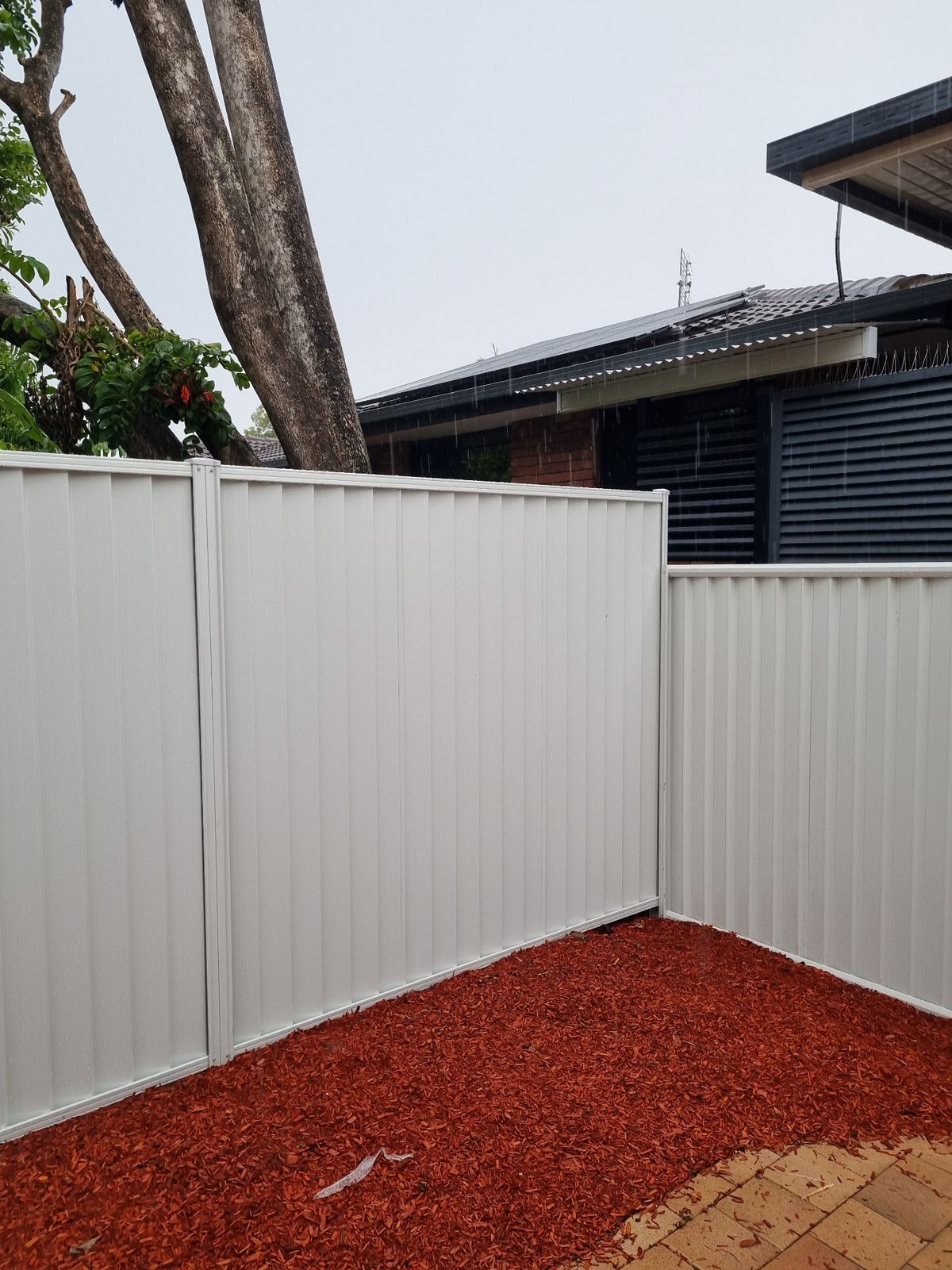 Cream Colorbond fence corner with a stepped panel